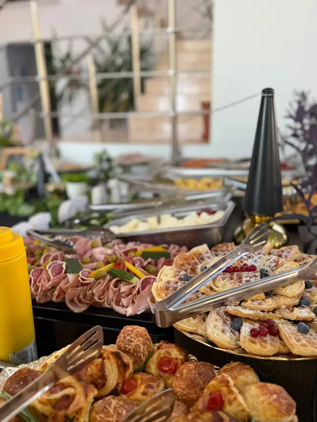 Detaliu de bufet: platouri cu mezeluri si chafing dish-uri cu preparate calde