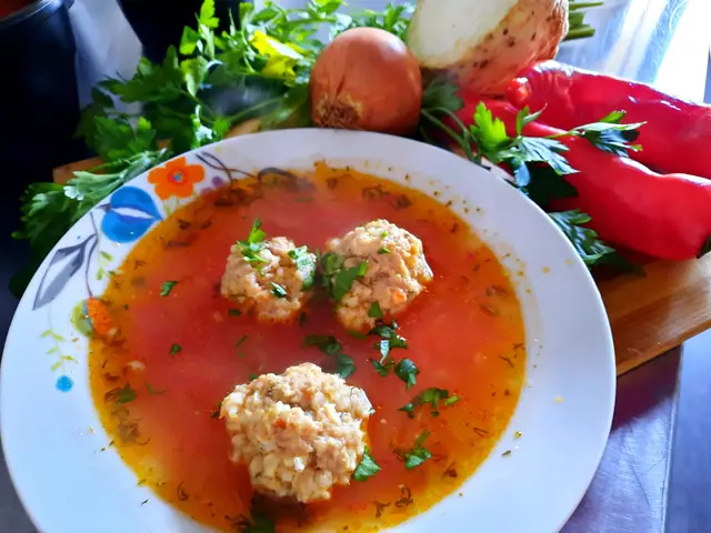 Ciorba de perisoare servita in farfurie, cu legume proaspete alaturi