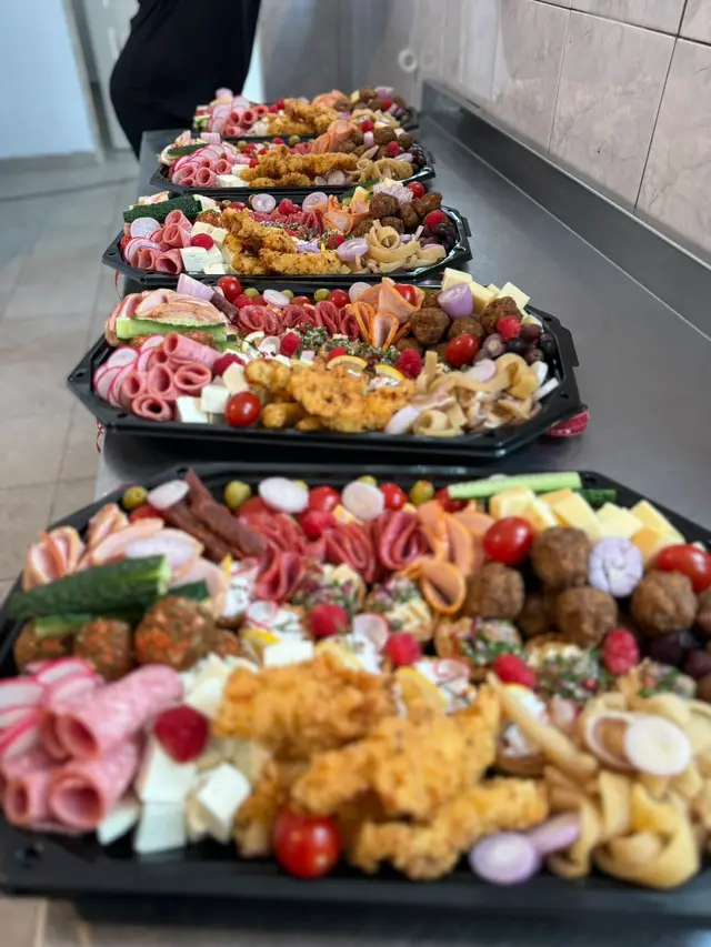 Trei platouri cu mezeluri, branzeturi, chiftele si legume, pregatite pentru livrare