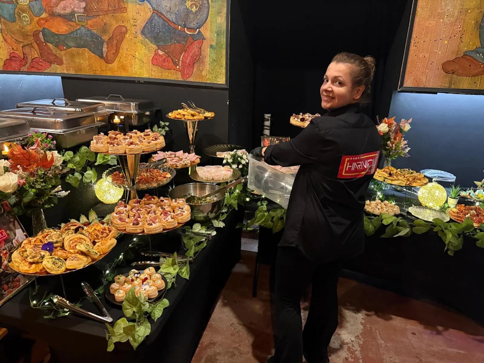 Membra a echipei Harnicu, in uniforma, langa bufetul de aperitive decorat cu verdeata